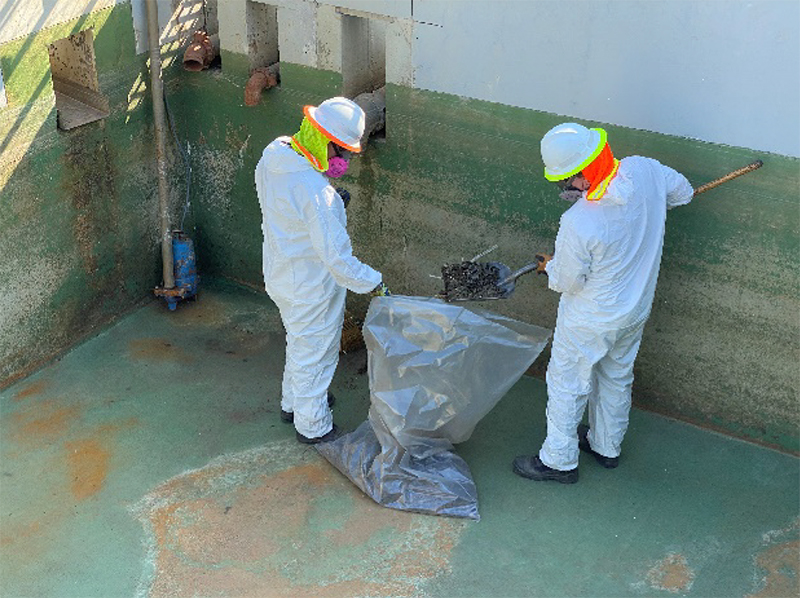 crew in hazmat suits dump debris into waste bags for disposal